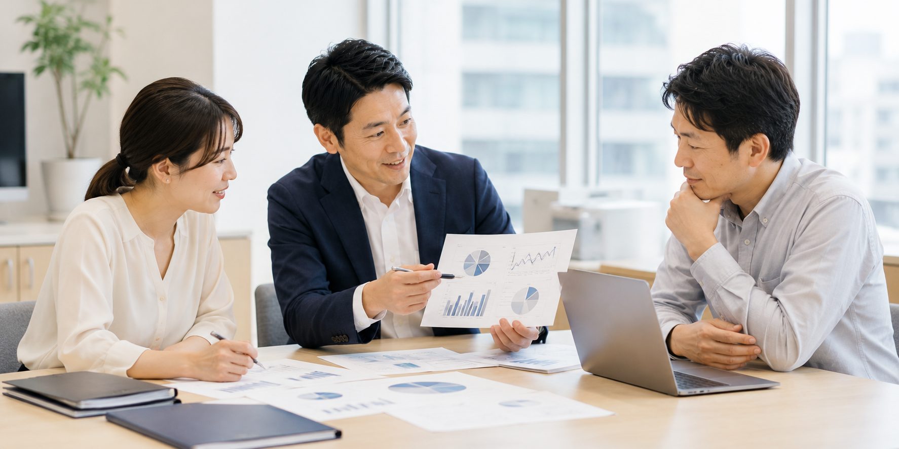 補助金の事業計画をグラフ資料とノートPCで打ち合わせする様子